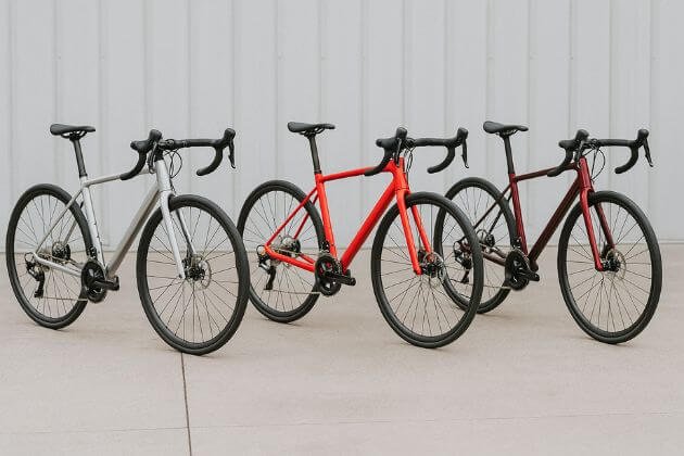 Drie moderne racefietsen met verschillende kleuren en schijfremmen voor een fietsenwinkel